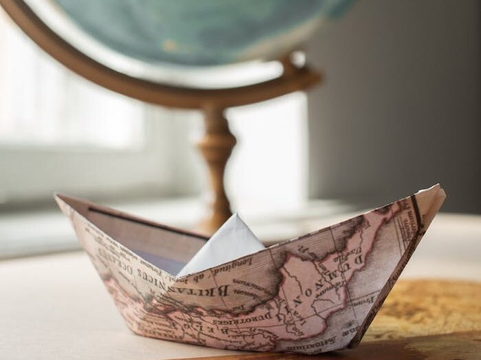 Paper boat with map near globe